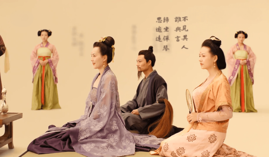 A gathering of elegantly dressed Tang Dynasty individuals seated in a serene environment with traditional calligraphy in the background.