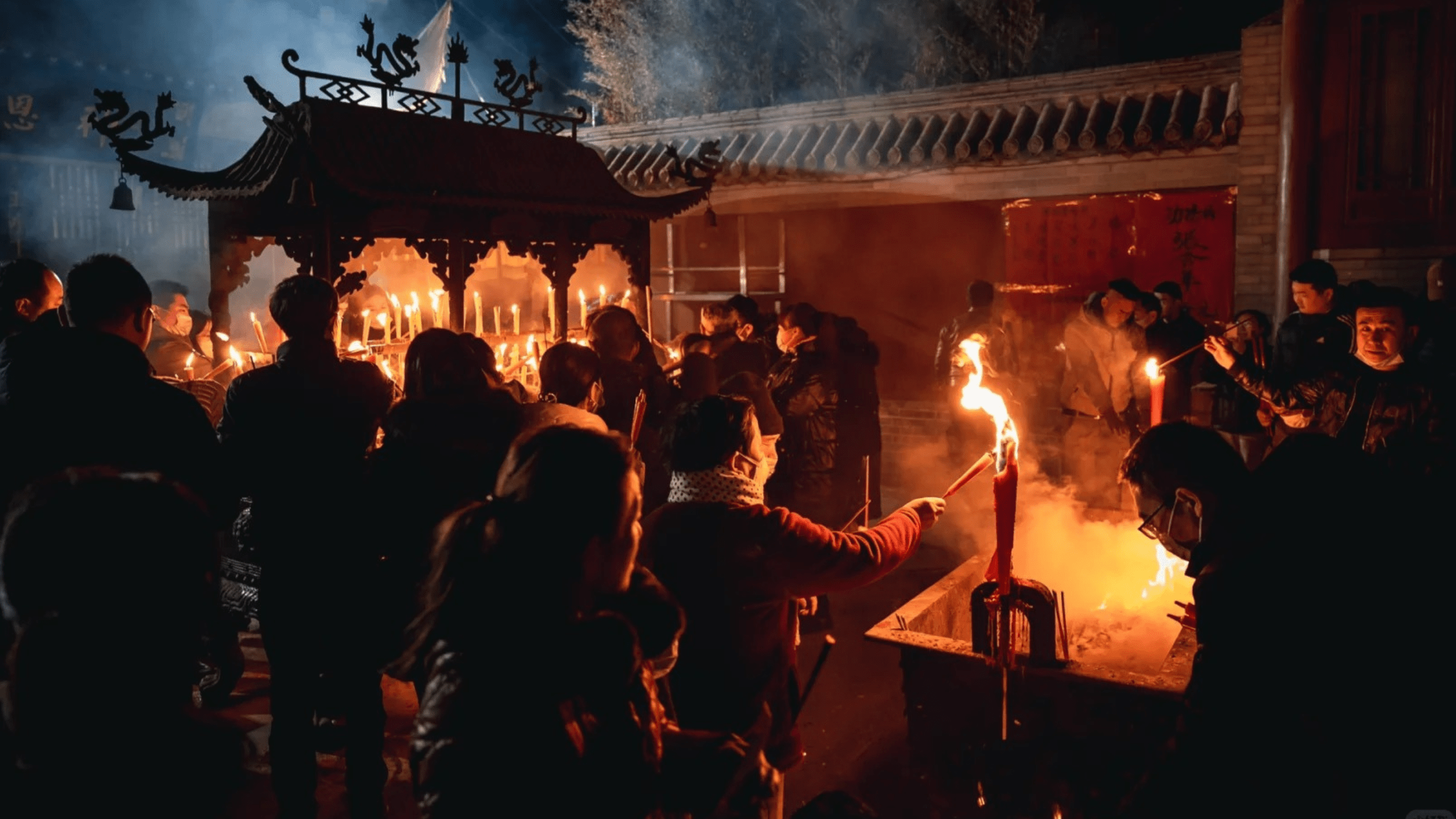 Community lighting incense and candles at a temple during modern ancestor worship practices.