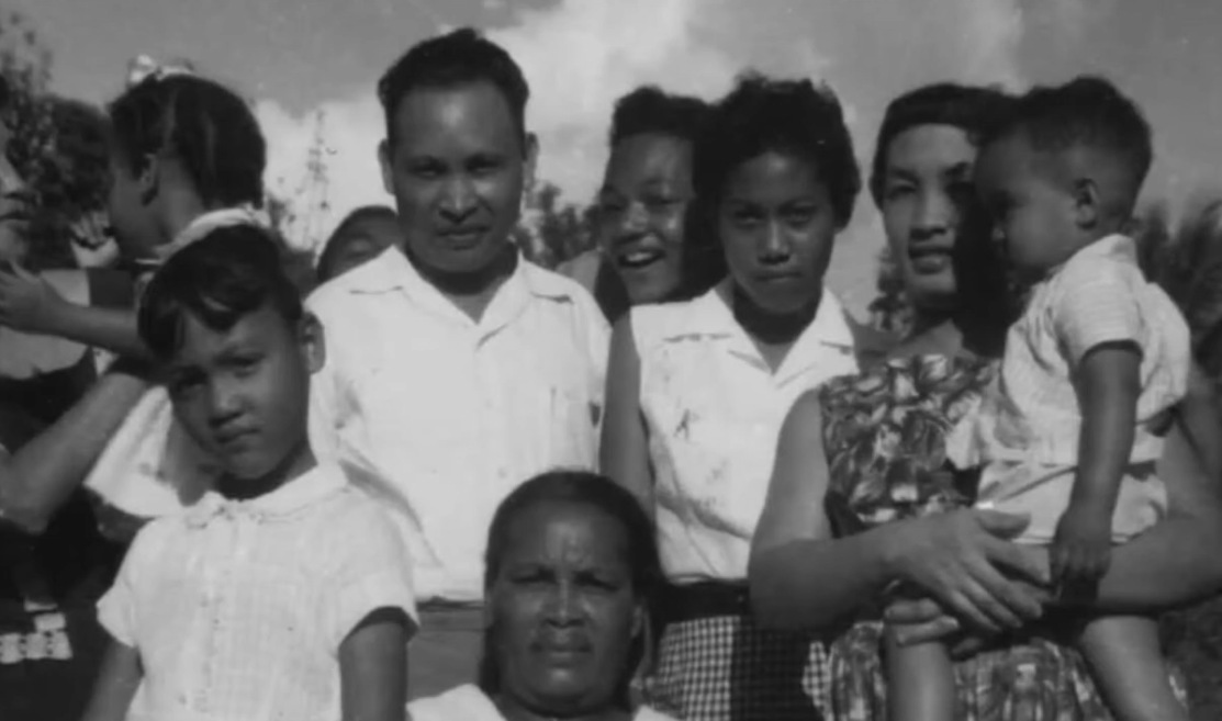 A mid-20th-century photograph showing a Chinese Jamaican family, including parents, children, and extended relatives, gathered outdoors.