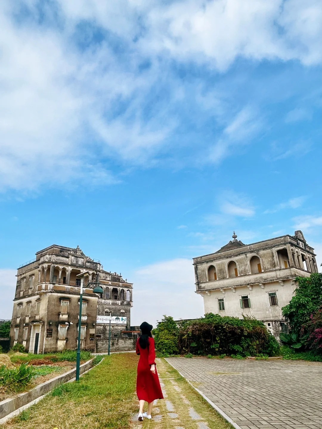 A traveler in a red dress walking through historic diaolou villages in Taishan.