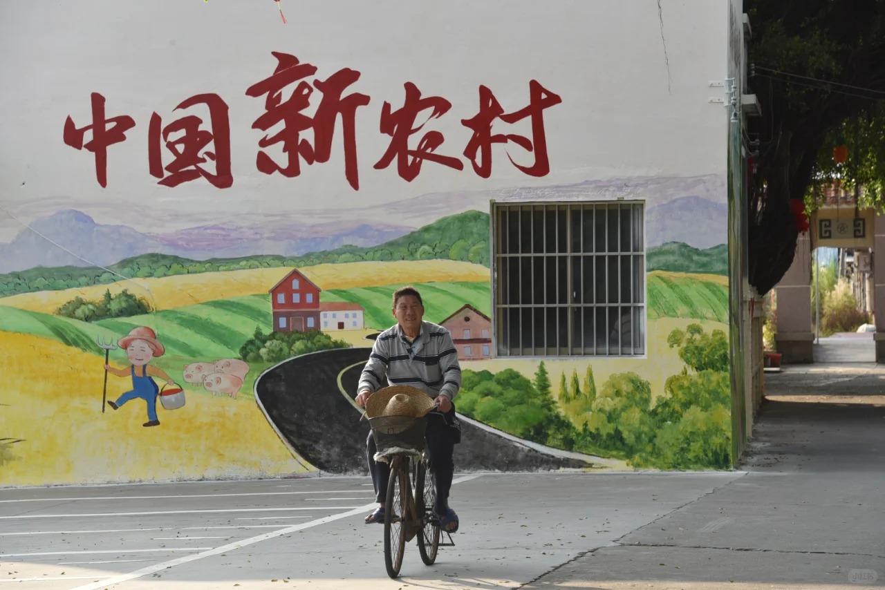 Xinhui village mural with vibrant countryside and a local man on a bicycle.