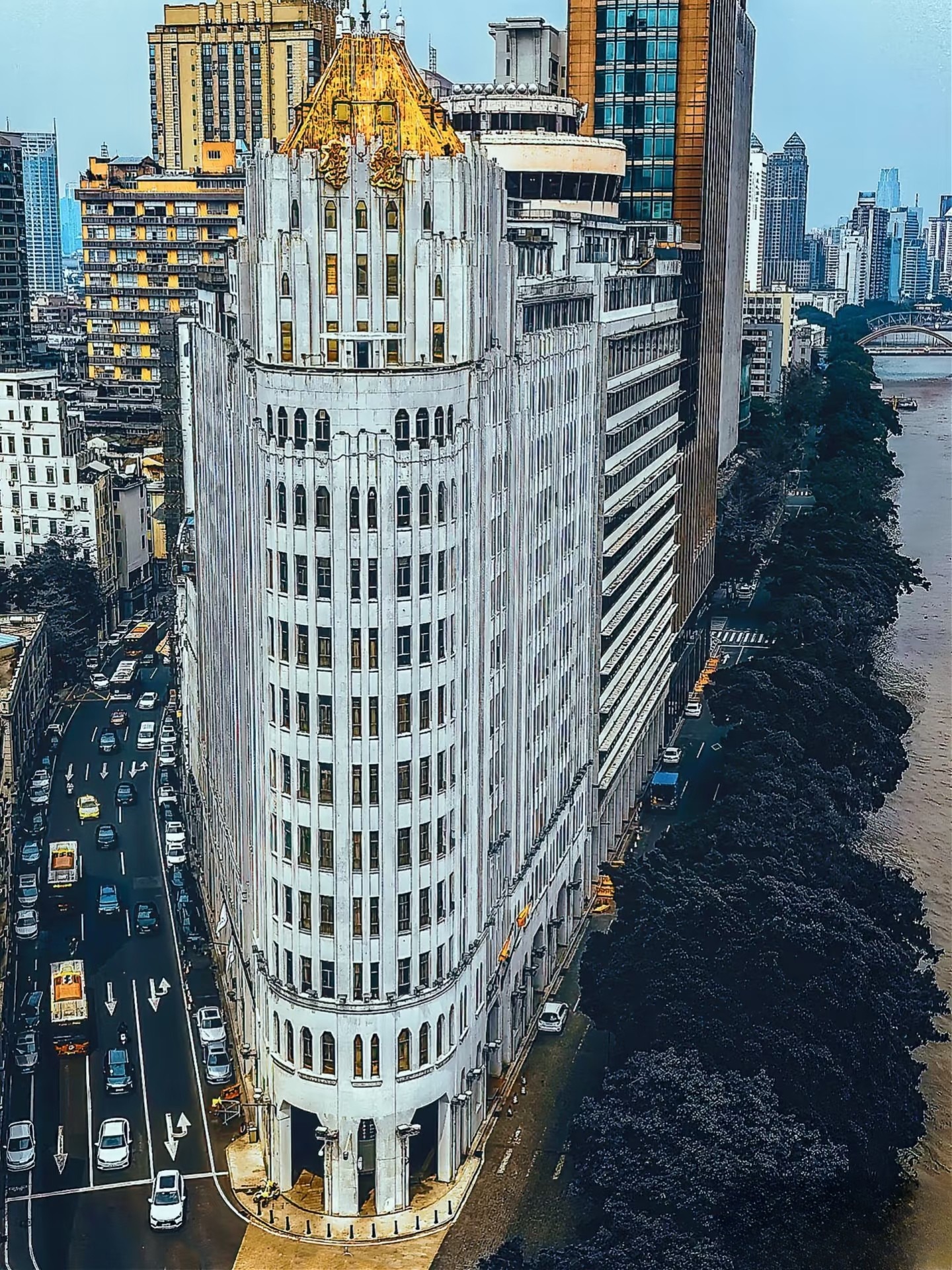The Aiqun Hotel in Guangzhou, a historic building with a golden roof, reflecting Chinese genealogy and ancestral hall diaspora contributions in a modern cityscape.