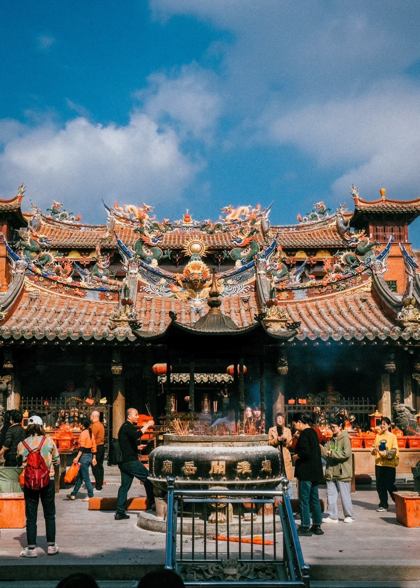 People gathered in a traditional Chinese ancestral hall in Fujian, with intricate decorations and an incense burner, honoring Chinese genealogy during a ritual.