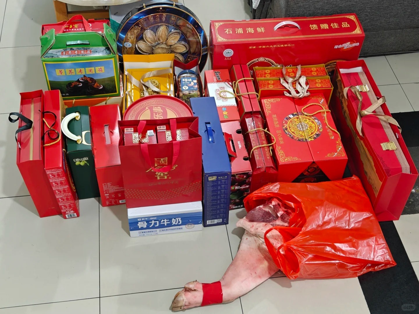 A collection of red gift boxes, food items, and a roasted pig on the floor, prepared for the Hui Men ritual in Guangdong’s marriage traditions.