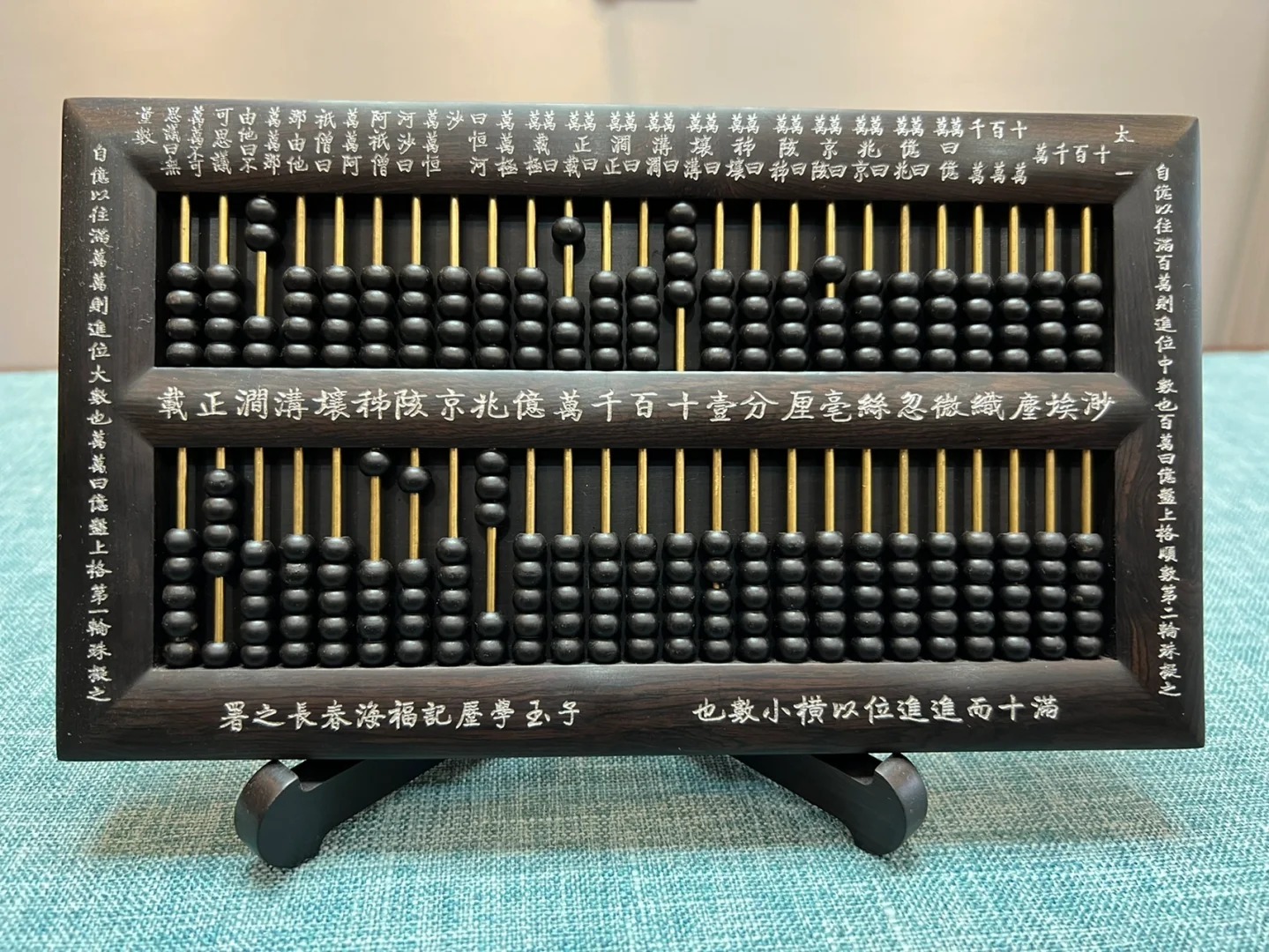 The Ziyu Suanpan, a high-order abacus with 45 rods and black beads, designed by Zhou Maoqi for complex calculations in naval engineering, displayed on a teal surface.