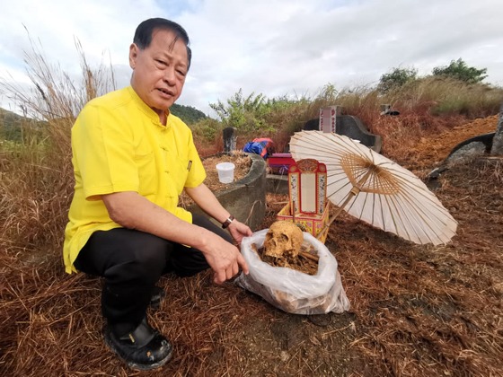 Taoist priest Mr. Wu carefully examining remains wrapped in a bag as part of the secondary burial process.