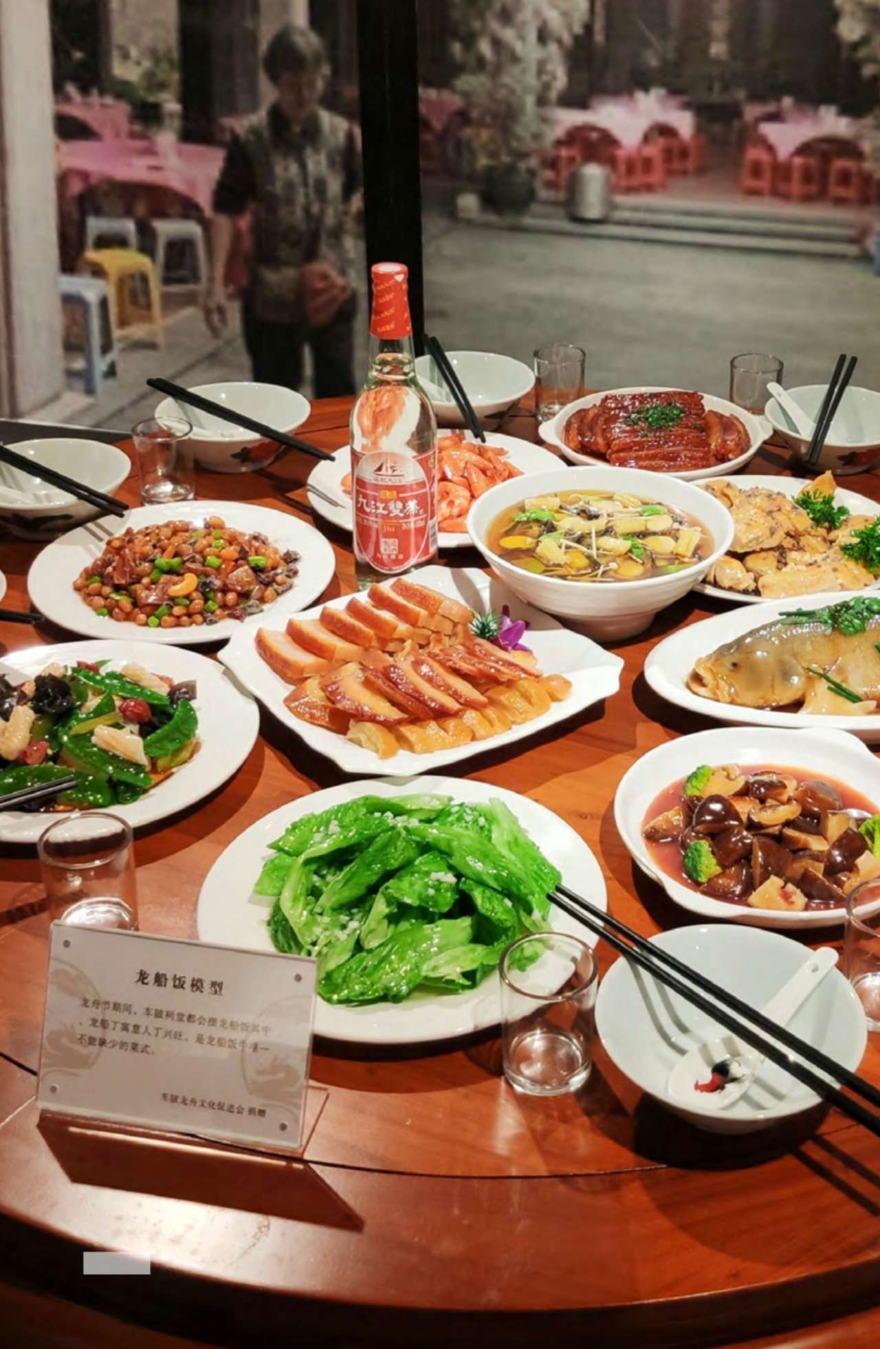 Assorted traditional dishes on a round banquet table for dragon boat meal during Dragon Boat Festival, symbolizing community and blessing.