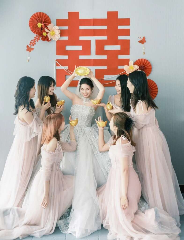 Bride holding traditional gold ingots surrounded by bridesmaids, celebrating rural wedding customs