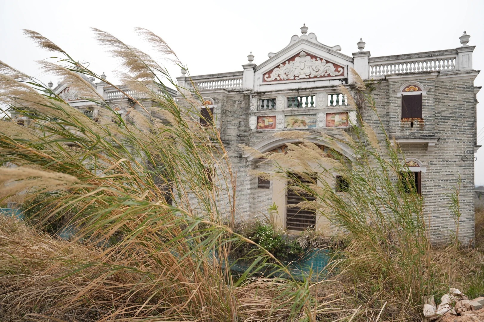 Decorative ancestral home behind tall grass in rural China
