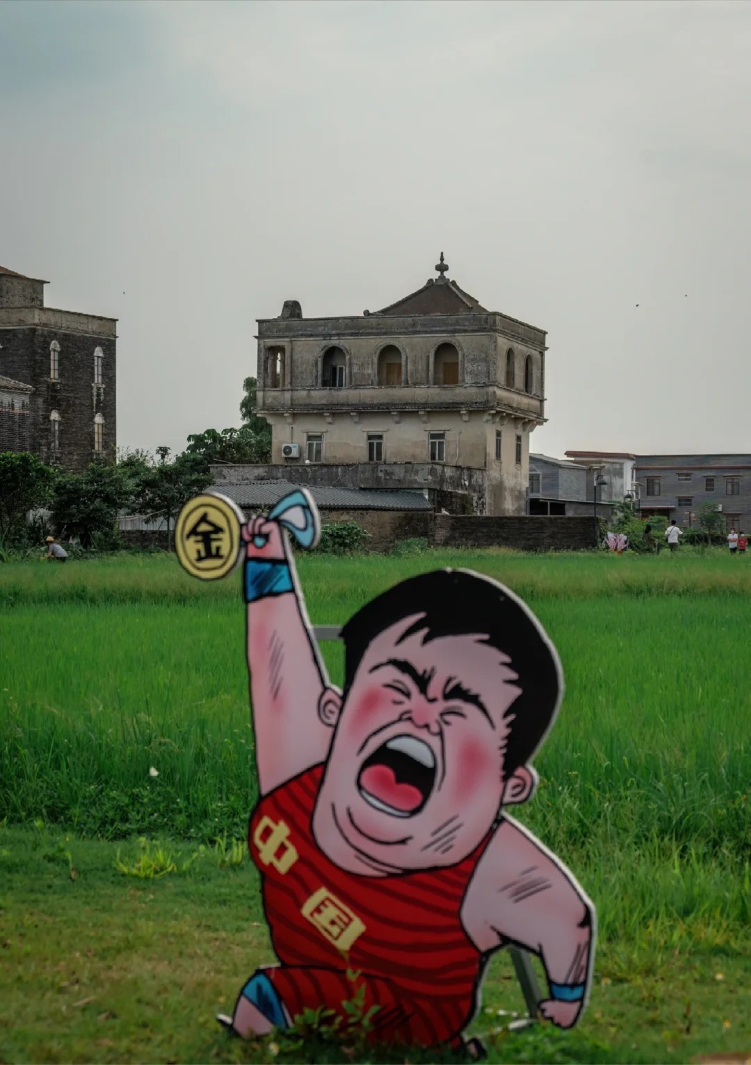 Cartoon cutout in front of historic homes in a rice field in rural China